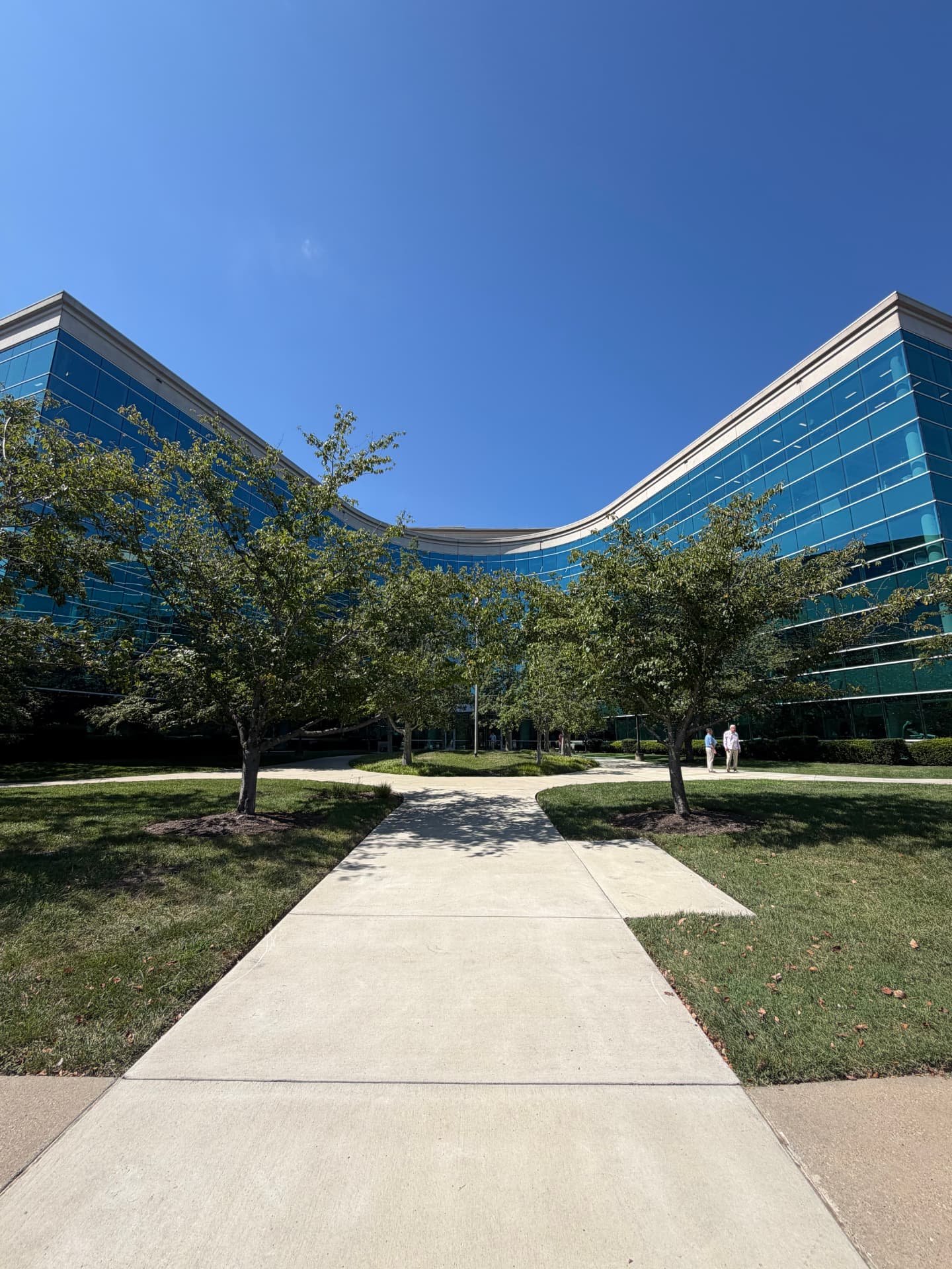 Highwoods Park West office building in Cool Springs, with a curved glass facade and a tree-lined walkway leading to the entrance